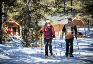 Deux personnes font de la raquette devant un chalet en bois à Champagny en Vanoise, France.