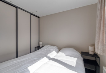 Dormitorio moderno en Natuurhoeve, Park Westerkogge, Países Bajos, con dos camas y luz natural desde la ventana.