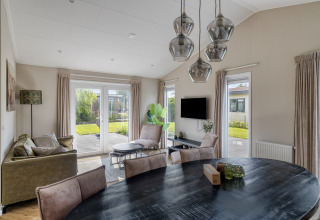 Salon moderne d’un lodge Natuurhoeve du parc Westerkogge aux Pays-Bas, avec vue sur jardin à travers de grandes fenêtres.