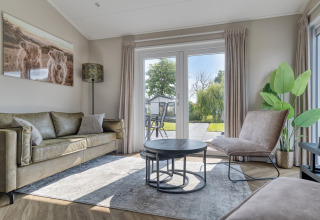 Soggiorno moderno al lodge Natuurhoeve, Park Westerkogge, Paesi Bassi, con vista sul giardino dalle finestre.