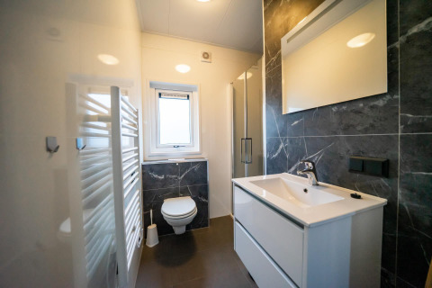 Moderne badkamer met hangtoilet, wastafel en spiegel in Pavilion 4+4 lodge bij EuroParcs Texel in Nederland.