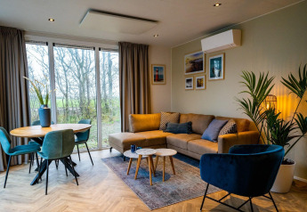 Moderne stue i Pavilion 4+4 på EuroParcs Texel, Holland, med sofa, spisebord og store vinduer.