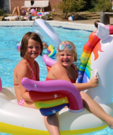 To glade børn leger på en stor enhjørning oppustelig badelegetøj i poolen på Vakantiepark Bonte Vlucht.