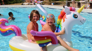 Due bambini felici giocano su un gonfiabile unicorno in piscina al Vakantiepark Bonte Vlucht nei Paesi Bassi.