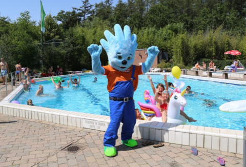 Maskottchen tanzt am Außenpool, während Kinder im Wasser schwimmen und spielen im Ferienpark Bonte Vlucht.