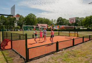 Bambini giocano su un campo polisportivo con canestri da basket a Camping Goorzicht, Olanda Settentrionale, Paesi Bassi.