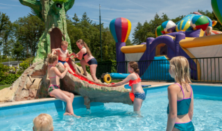 Bambini giocano in piscina con scivolo e gonfiabili al campeggio Goorzicht nei Paesi Bassi.