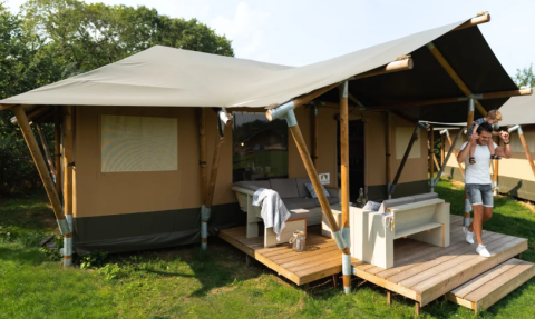 Glamping-Zelt auf Camping Goorzicht in Nordholland mit Vater und Kind auf der sonnigen Terrasse.