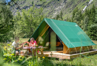 Due persone fanno un picnic davanti a una tenda glamping a Huttopia Vanoise in Alvernia-Rodano-Alpi.