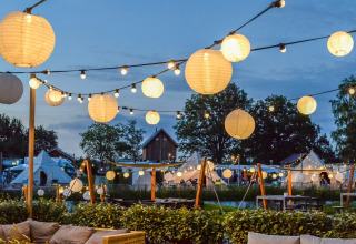 Evening at Holiday Park Mölke in Overijssel, Netherlands with string lights and tents visible.