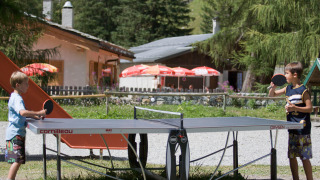 Two boys play table tennis outdoors at Huttopia Vanoise – Champagny glamping in Auvergne-Rhône-Alpes, France.