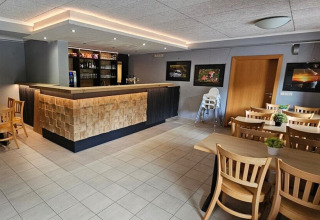 Moderno bar e zona pranzo con tavoli in legno al Camping Reiler, Clervaux, Lussemburgo.