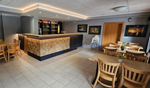 Moderno bar e zona pranzo con tavoli in legno al Camping Reiler, Clervaux, Lussemburgo.