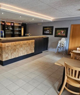 Modern eingerichtete Bar mit Holztischen im Camping Reiler im Kanton Clervaux, Luxemburg.