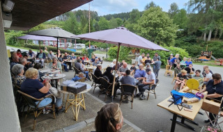 Menschen versammeln sich zu einer Veranstaltung im Freien im Ferienpark Camping Reiler, Luxemburg.
