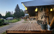 Wooden terrace with string lights at Camping Reiler holiday park in Clervaux, Luxembourg, with camper van.