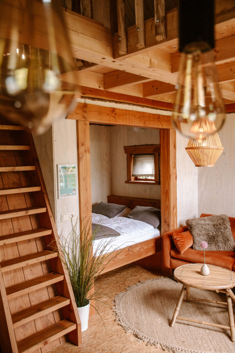 Intérieur en bois chaleureux au Holiday Park Mölke à Overijssel, Pays-Bas, avec lit, canapé et mezzanine.