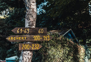 Panneaux de bois à Camping Reiler, Luxembourg, indiquant le tir à l’arc et différents numéros de chambres.
