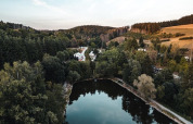 Vista aerea di Camping Reiler nel Cantone Clervaux, Lussemburgo, con lago, foresta e abitazioni vacanza.