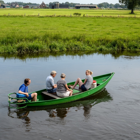Cuatro personas disfrutan de un paseo en bote por un canal en Holiday Park Mölke en el campo de Overijssel.