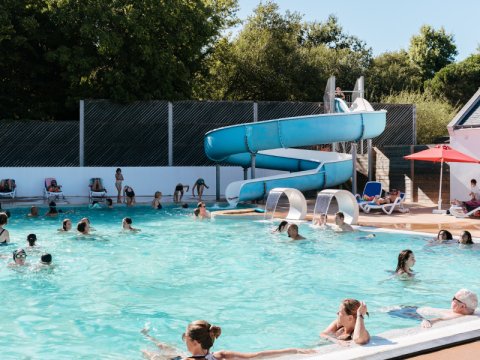 Piscine extérieure au Flower Camping Le Kerarno, Bretagne, familles nageant et toboggan bleu visible.