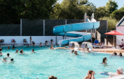 Piscine extérieure au Flower Camping Le Kerarno, Bretagne, familles nageant et toboggan bleu visible.
