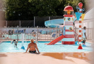 Des enfants jouent dans la piscine avec toboggan et phare au Flower Camping Le Kerarno en Bretagne, France.