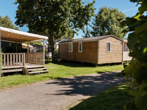 Houten chalets en schaduwrijke terrassen in een groene omgeving op Flower Camping Le Kerarno, Bretagne, Frankrijk.