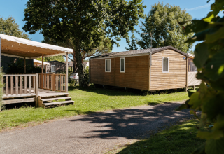Holzhütten mit Veranda in einer grünen, sonnigen Umgebung im Flower Camping Le Kerarno, Bretagne, Frankreich.