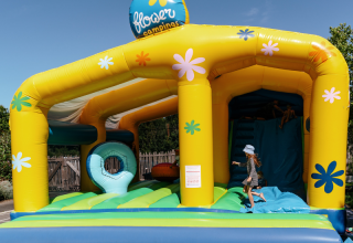 Niño jugando en un castillo hinchable de colores en Flower Camping Le Kerarno, parque vacacional en Bretaña, Francia.