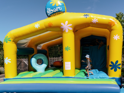 Child playing on a colorful bouncy castle at Flower Camping Le Kerarno, a holiday park in Brittany, France.