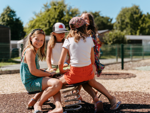 Children playing together at the playground in Flower Camping Le Kerarno holiday park in Brittany, France.