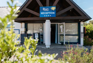 Ingang van de receptie van Flower Camping Le Kerarno, een vakantiepark in Bretagne, Frankrijk, met groen.