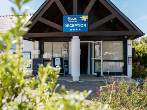 Ingang van de receptie van Flower Camping Le Kerarno, een vakantiepark in Bretagne, Frankrijk, met groen.