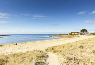 Zandstrand en rustig water nabij Saint-Philibert, Bretagne, Frankrijk, met enkele mensen die wandelen.