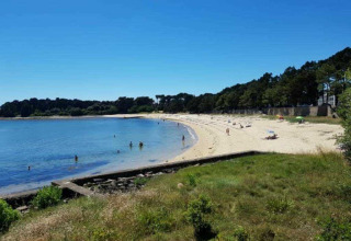 Ruhige Sandstrandansicht bei Flower Camping Le Kerarno, Bretagne, Frankreich, mit klarem Himmel und Bäumen.
