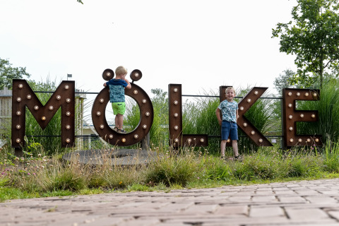 Zwei Kinder spielen an einem großen 'MÖLKE'-Schild im Ferienpark Mölke in Overijssel, Niederlande.