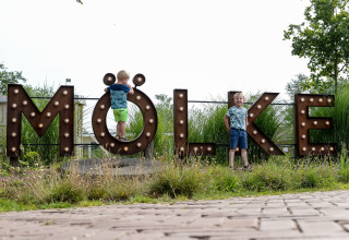 Due bambini giocano vicino a una grande scritta 'MÖLKE' al parco vacanze Mölke a Overijssel, Paesi Bassi.