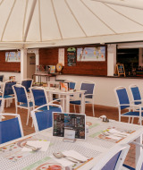 Area ristorante all'aperto con sedie blu e tavoli bianchi al Flower Camping Le Kerarno in Bretagna, Francia.