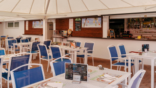 Area ristorante all'aperto con sedie blu e tavoli bianchi al Flower Camping Le Kerarno in Bretagna, Francia.
