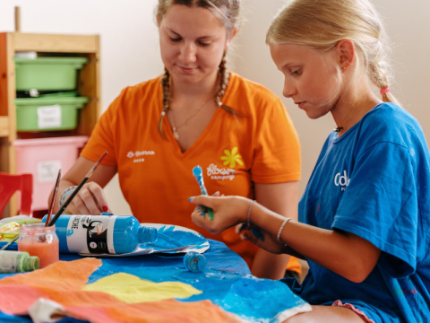 A child and an adult painting together at a table in Flower Camping Le Kerarno, Brittany, France.
