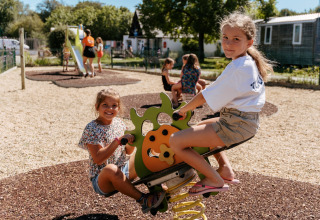 To piger leger på en vippe i en legeplads på Flower Camping Le Kerarno, en feriepark i Bretagne, Frankrig.