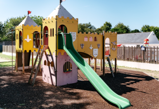 Burgförmiger Spielplatz mit grüne Rutsche im Flower Camping Le Kerarno, einem Ferienpark in der Bretagne.