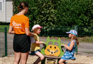 Children play on a playground under adult supervision at Flower Camping Le Kerarno in Brittany, France.