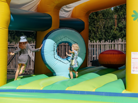 Niños jugando en un colorido castillo hinchable en Flower Camping Le Kerarno, un parque vacacional en Bretaña.