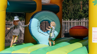 Bambini che giocano su un castello gonfiabile colorato al Flower Camping Le Kerarno in Bretagna, Francia.