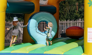 Bambini che giocano su un castello gonfiabile colorato al Flower Camping Le Kerarno in Bretagna, Francia.