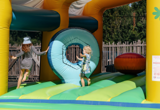 Children playing on a colorful inflatable bouncy castle at Flower Camping Le Kerarno holiday park in Brittany.