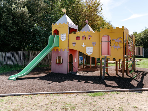 Parque infantil con tema de castillo y tobogán en Flower Camping Le Kerarno, Bretaña, Francia.
