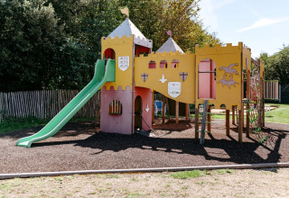 Parque infantil con tema de castillo y tobogán en Flower Camping Le Kerarno, Bretaña, Francia.